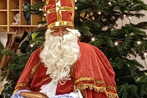 Ein als Nikolaus verkleideter Mann sitzt vor einem Tannenbaum